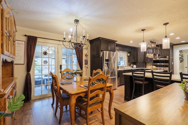 dining area featuring ornamental molding, light wood-type flooring, a textured ceiling, and a chandelier