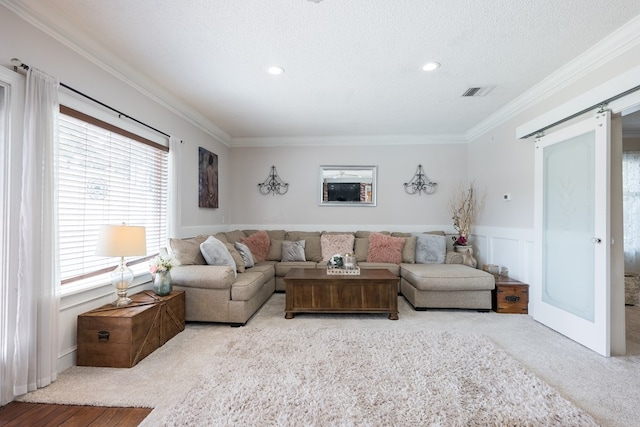 living room with light colored carpet, ornamental molding, a barn door, and a textured ceiling