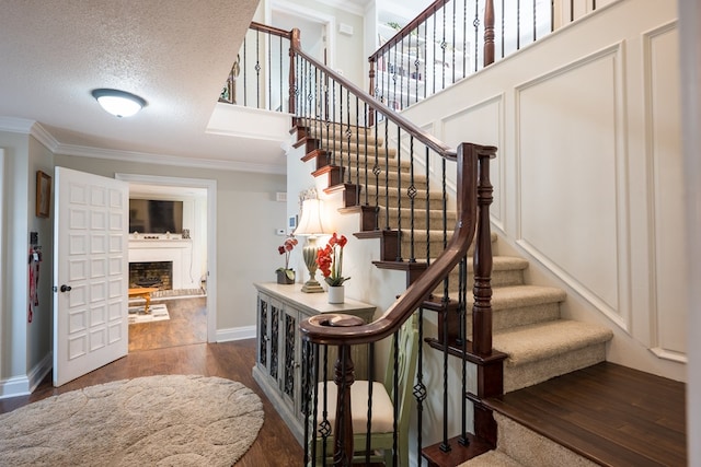 stairway featuring crown molding, a textured ceiling, and hardwood / wood-style flooring