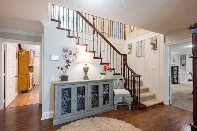 stairs with crown molding, wood-type flooring, and a textured ceiling