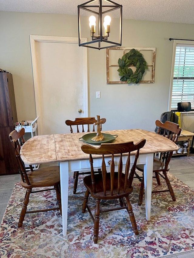 dining room featuring a textured ceiling, a notable chandelier, and wood finished floors