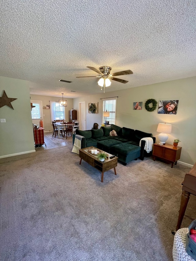 carpeted living area featuring a textured ceiling, ceiling fan, visible vents, and baseboards