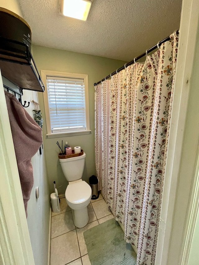 full bathroom with tile patterned floors, a textured ceiling, and toilet
