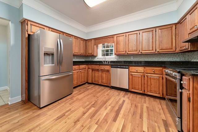 kitchen featuring crown molding, appliances with stainless steel finishes, backsplash, and light wood-type flooring