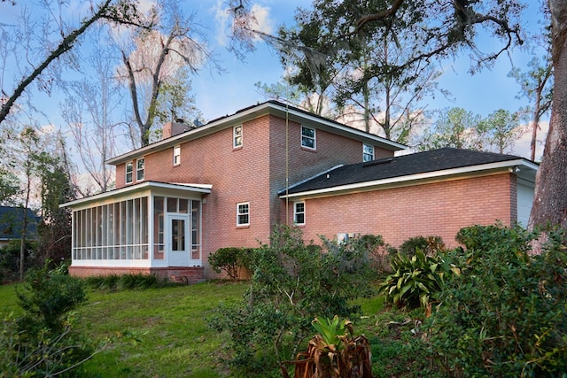 rear view of house with a sunroom and a lawn