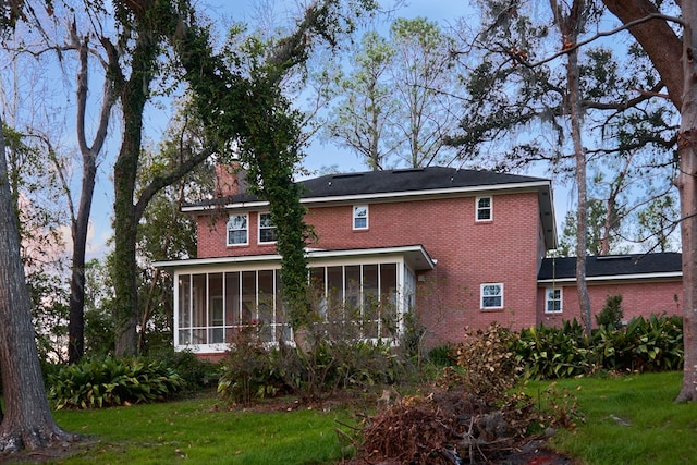 back of house featuring a sunroom and a lawn