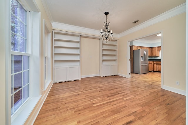 unfurnished dining area with crown molding, light hardwood / wood-style flooring, a textured ceiling, and a chandelier