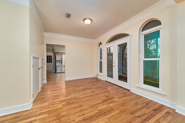 spare room with crown molding, a textured ceiling, and light hardwood / wood-style floors