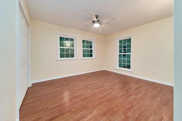 empty room with ceiling fan, light hardwood / wood-style flooring, and a textured ceiling