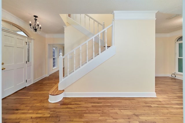 foyer featuring ornamental molding, wood-type flooring, and a notable chandelier