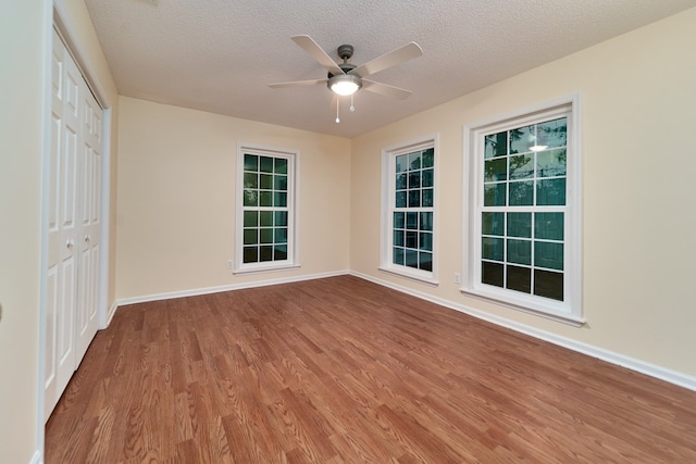 empty room featuring ceiling fan, hardwood / wood-style floors, and a textured ceiling