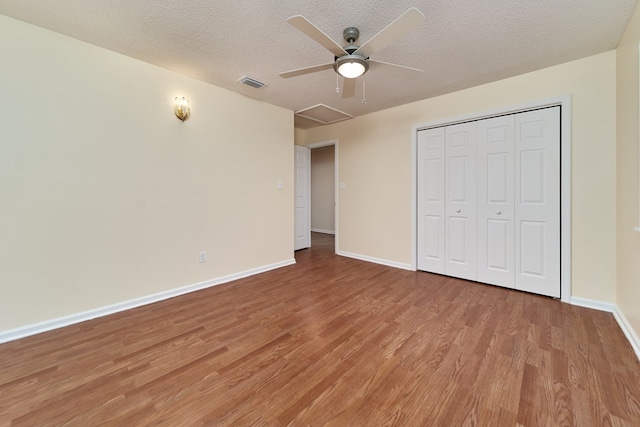 unfurnished bedroom with ceiling fan, hardwood / wood-style flooring, a closet, and a textured ceiling