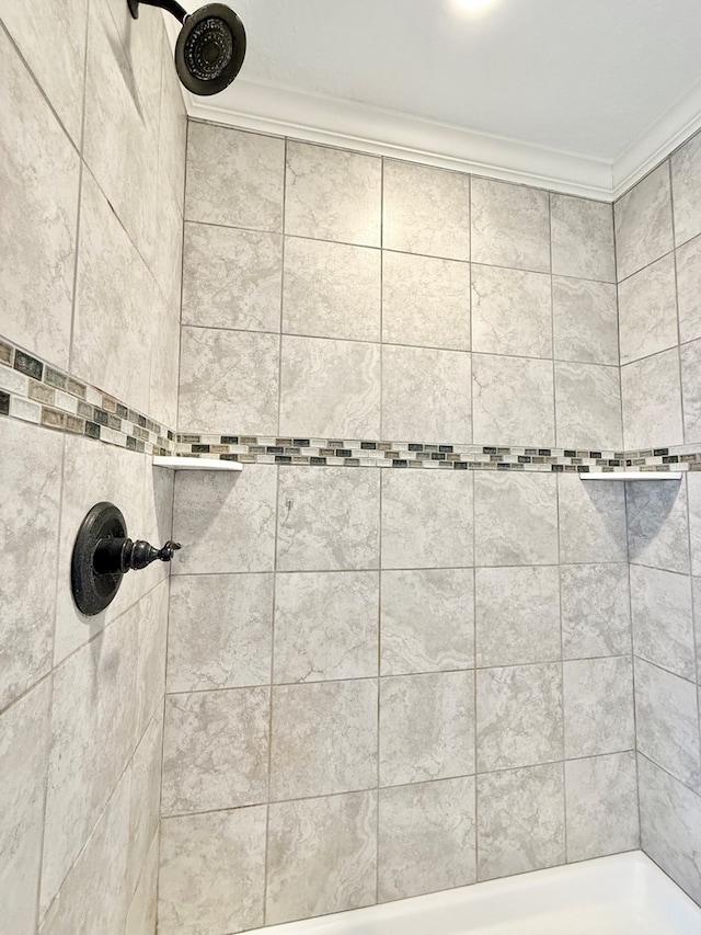 bathroom featuring a tile shower and crown molding