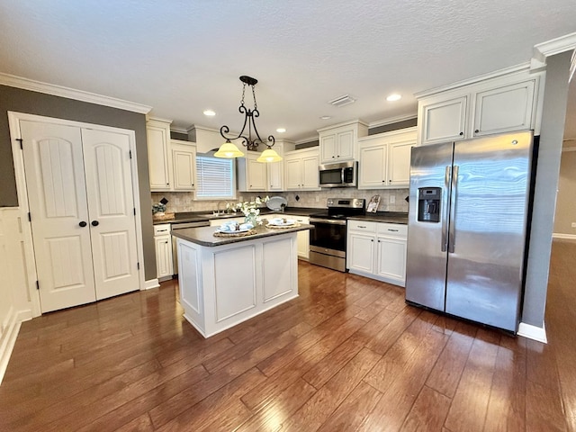 kitchen featuring decorative light fixtures, stainless steel appliances, a kitchen island, crown molding, and sink