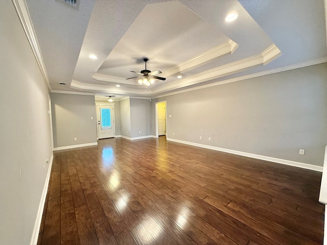 unfurnished room with ceiling fan, crown molding, a raised ceiling, and dark hardwood / wood-style floors