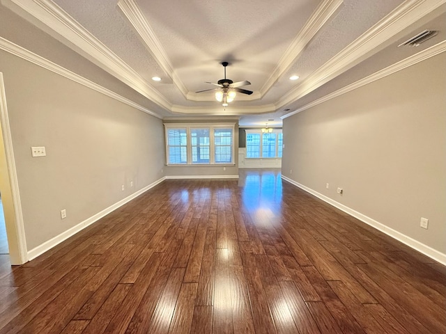 empty room with dark hardwood / wood-style flooring, ceiling fan, a tray ceiling, and ornamental molding