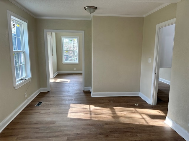 unfurnished room with ornamental molding, dark wood-type flooring, and a healthy amount of sunlight