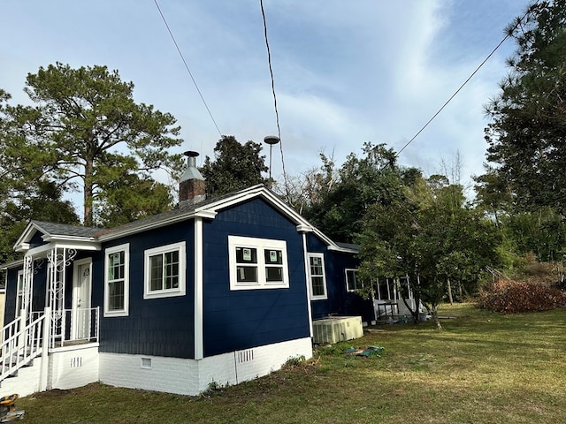 view of side of property featuring a lawn and central AC