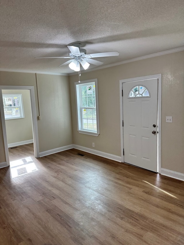 foyer entrance featuring ceiling fan, ornamental molding, a textured ceiling, and light wood-type flooring