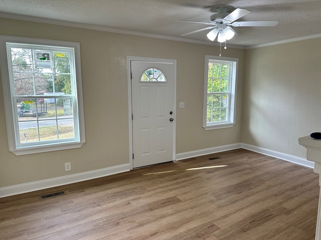 foyer featuring a textured ceiling, light wood-type flooring, ceiling fan, and ornamental molding