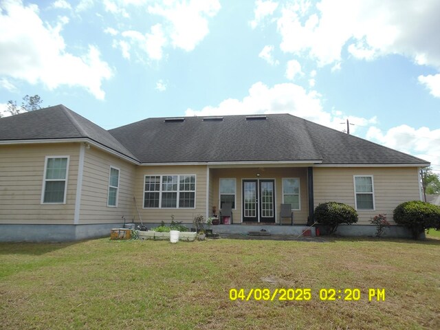rear view of property with a lawn and roof with shingles