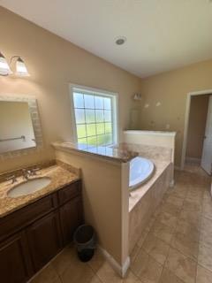 full bath with tile patterned floors, a garden tub, and vanity