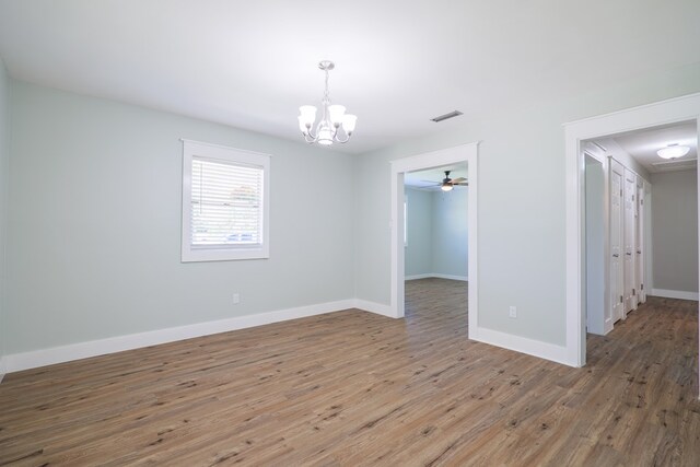 empty room with ceiling fan with notable chandelier and hardwood / wood-style flooring