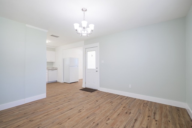 empty room featuring light wood-type flooring and a chandelier