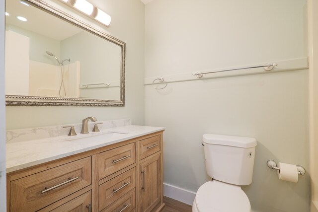 bathroom featuring a shower, hardwood / wood-style flooring, vanity, and toilet