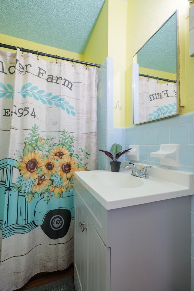 bathroom featuring vanity, a textured ceiling, and tile walls