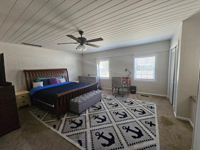 carpeted bedroom featuring ceiling fan, brick wall, and wooden ceiling