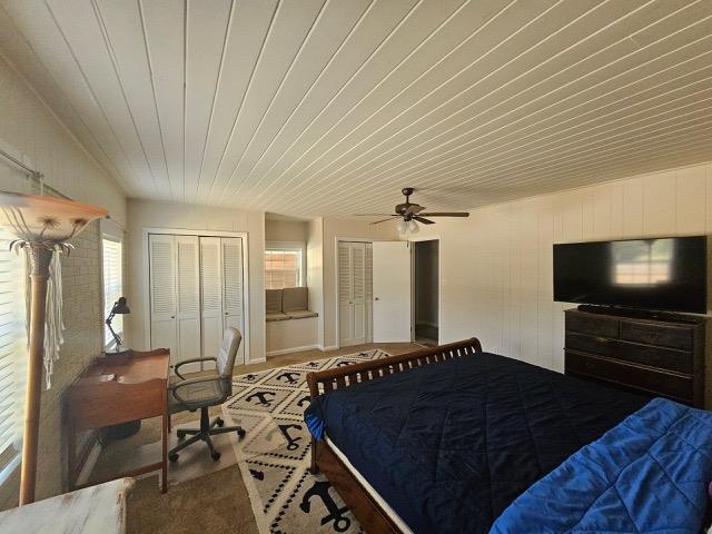 bedroom with two closets, wooden ceiling, and ceiling fan