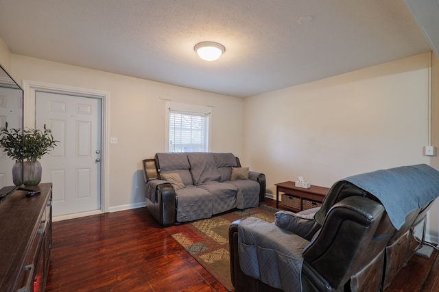 living room featuring dark wood-type flooring and a textured ceiling