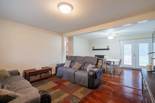 living room featuring ceiling fan, a fireplace, dark hardwood / wood-style flooring, and french doors