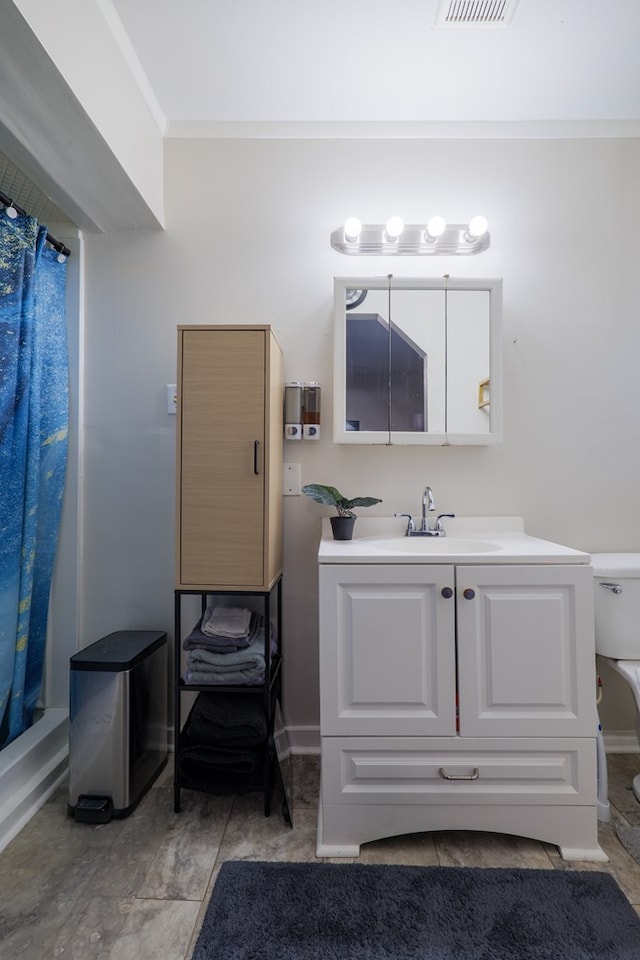 bathroom featuring ornamental molding, vanity, and toilet