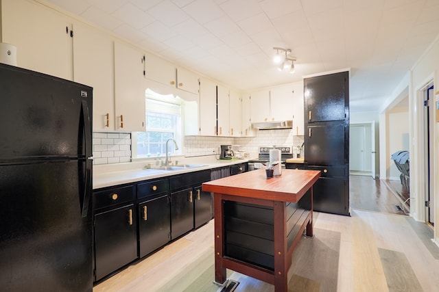 kitchen featuring black refrigerator, white cabinetry, sink, backsplash, and stainless steel range with electric stovetop