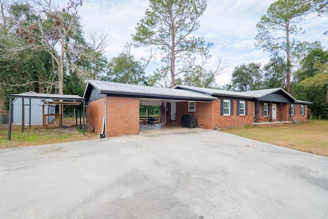 ranch-style house featuring a front yard, a carport, and a storage unit