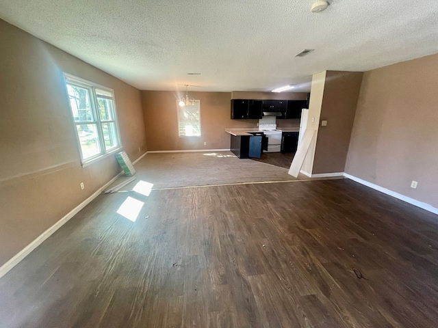 unfurnished living room with visible vents, dark wood-style floors, baseboards, and a textured ceiling