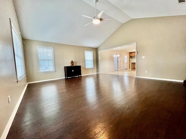 unfurnished living room featuring ceiling fan with notable chandelier, dark hardwood / wood-style floors, and lofted ceiling