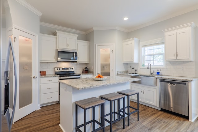 kitchen with white cabinetry, appliances with stainless steel finishes, a center island, and sink