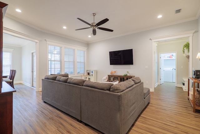 living room featuring crown molding, ceiling fan, wood-type flooring, and washer and dryer