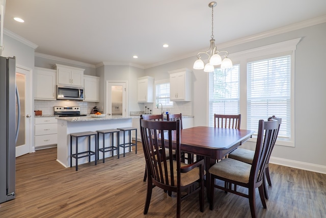 dining room with ornamental molding, dark wood-type flooring, sink, and a notable chandelier