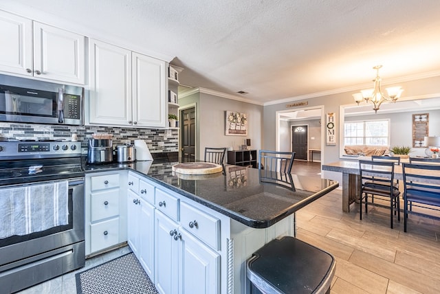 kitchen with white cabinetry, decorative light fixtures, kitchen peninsula, and appliances with stainless steel finishes