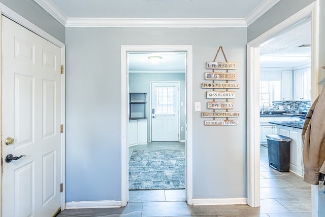 corridor with crown molding, a healthy amount of sunlight, and light tile patterned floors