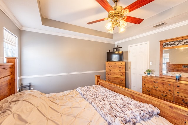 bedroom with crown molding, ceiling fan, a tray ceiling, and multiple windows