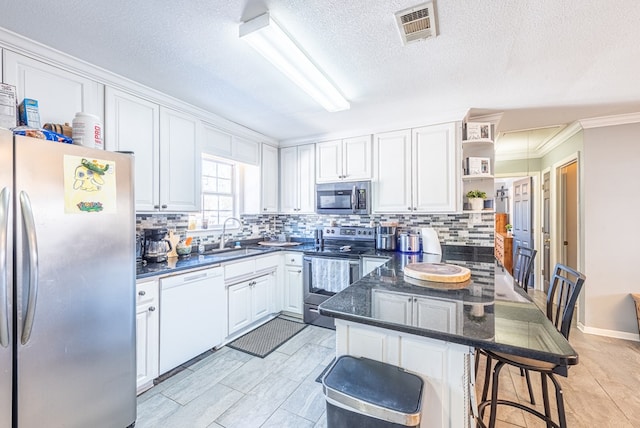 kitchen featuring sink, white cabinetry, backsplash, stainless steel appliances, and a kitchen bar