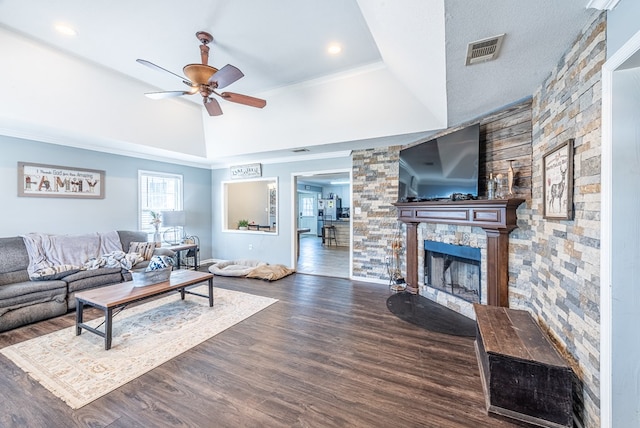 living room with ceiling fan, dark hardwood / wood-style flooring, a raised ceiling, and a stone fireplace