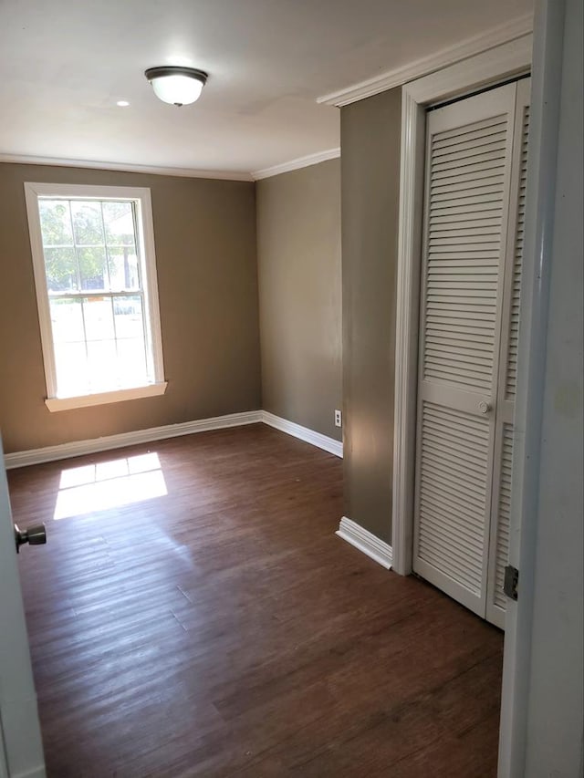 unfurnished bedroom featuring dark hardwood / wood-style flooring, a closet, and ornamental molding