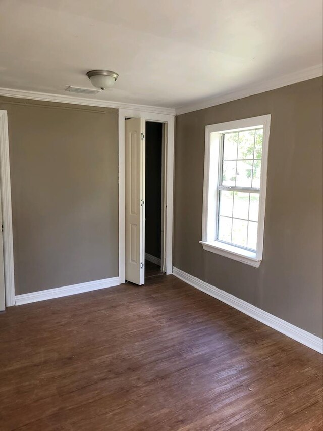 empty room with dark hardwood / wood-style flooring and ornamental molding