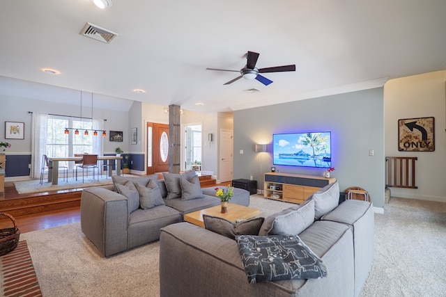 living area featuring crown molding, a ceiling fan, visible vents, and baseboards